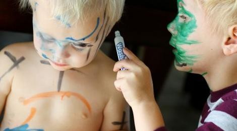 Zwei Kleinkinder malen sich gegenseitig mit Farbstiften an.