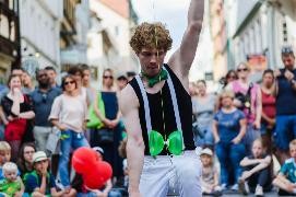 Jongleur mit grüner Fliege und grünem Diabolo vor Publikum in Altstadtstraße
