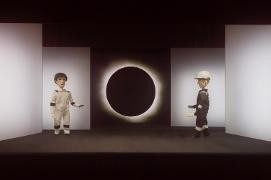 Zwei Marionetten befinden sich vor einem hell-dunklem Hintergrund